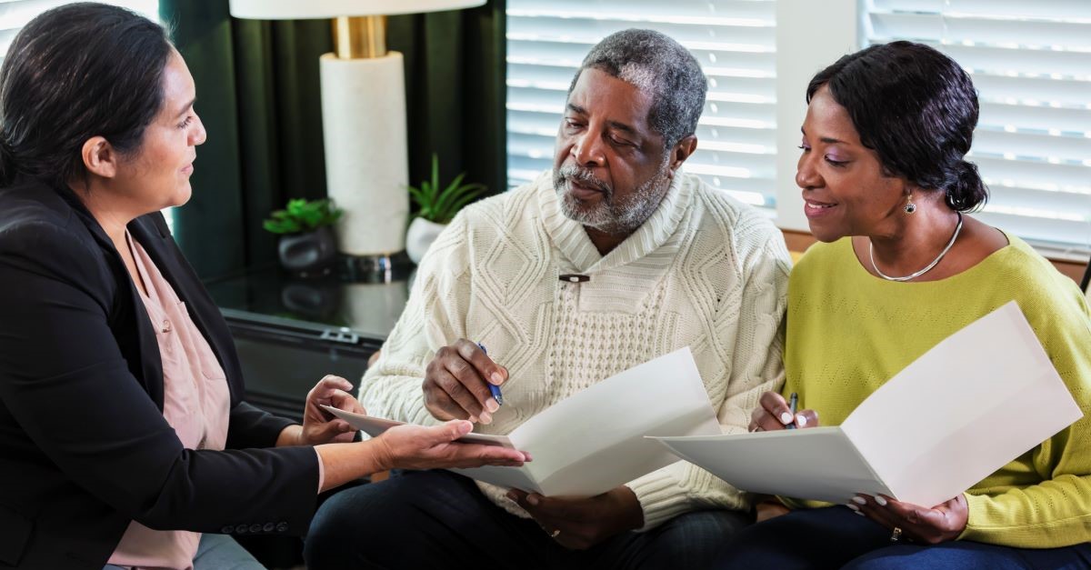An older couple signing documents with their agent