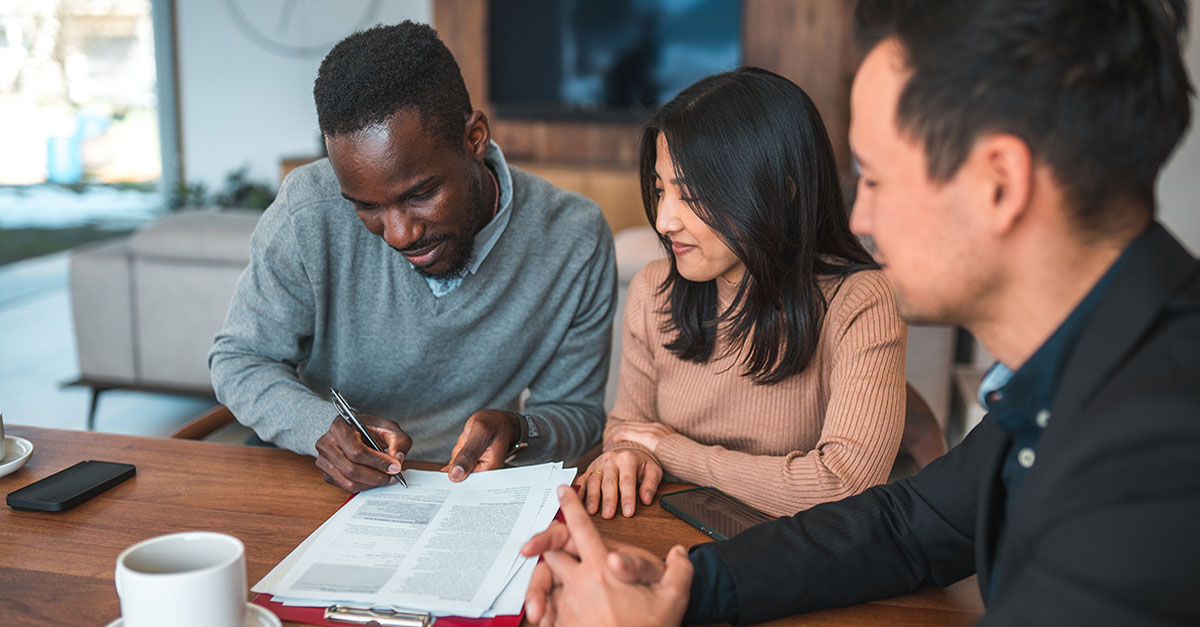 A couple signing closing documents in an office