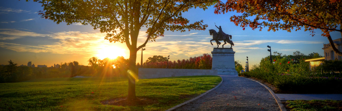 Stature of man on horse in park at sunrise